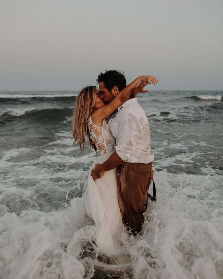 Couple enlacé au bord de la mer, robe de mariée sur mesure