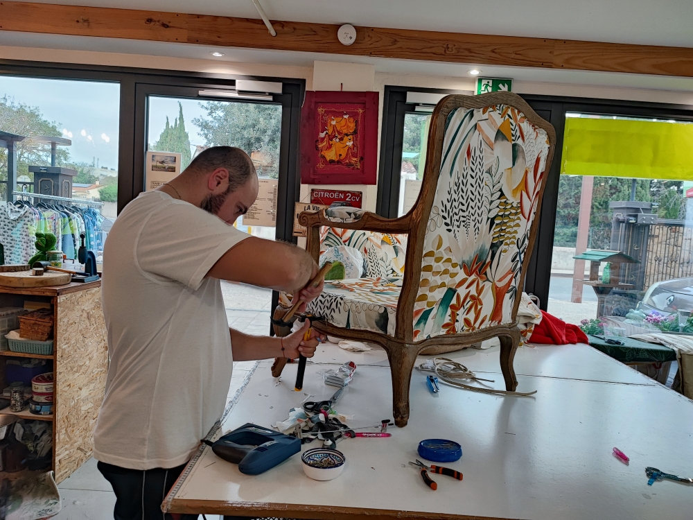 Artisan retapissant un fauteuil avec tissu fleuri