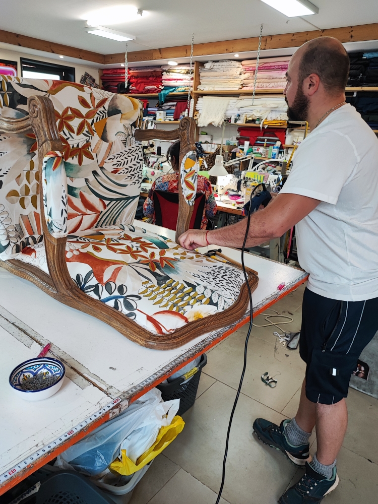 Artisan tapissier retapissant un fauteuil dans l'atelier