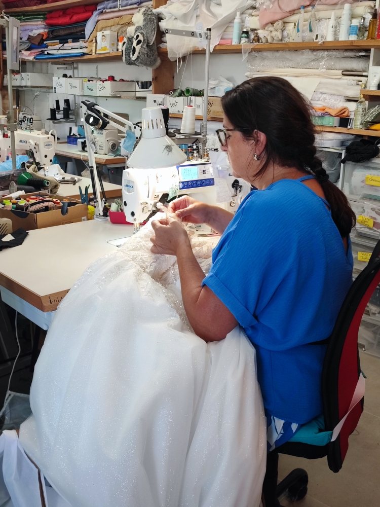 Couturière cousant une robe de mariée en atelier